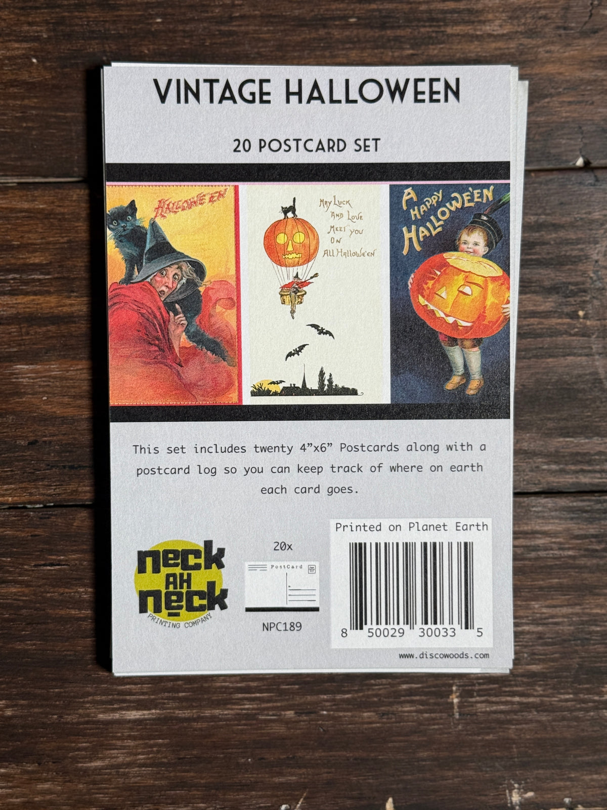 Vintage Halloween 20 postcard set in its back cover packaging, displayed flat on a dark wood background. The packaging features three vintage Halloween illustrations and the 'neckahneck' brand logo.